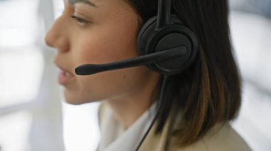 Bulanık bir geçmişe karşı kulaklık takan genç bir İspanyol kadının profili profesyonel iletişimi sembolize ediyor..