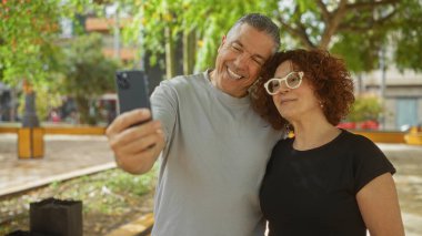 Şehir parkında selfie çeken orta yaşlı bir çift bir aşk ve neşe anı yakalıyorlar..