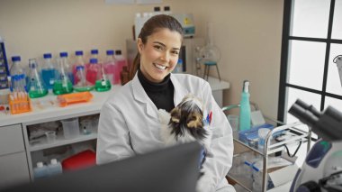 Laboratuar işyerinde bisiklet teriyeri tutan laboratuvar önlüklü, gülümseyen bir İspanyol kadın..