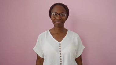 Kendine güvenen bir kadın, gözlük takan genç bir Afrikalı Amerikalı, izole edilmiş pembe arka planda küçük bir işaret konseptiyle el kol hareketi yapıyor.