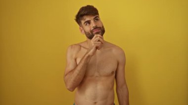 Mutlu yüzü ve fikri olan İspanyol asıllı genç adam, sarı izole edilmiş arka planda bir parmağını göstererek, bir numara