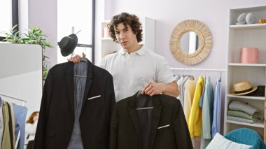 Modern bir soyunma odasında takım elbise seçen yakışıklı İspanyol bir adam..