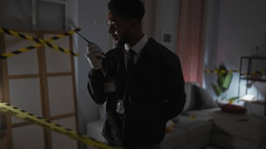 Afrika kökenli Amerikalı erkek dedektif olay yerinde telsiz kullanıyor.