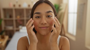 Genç bir kadın, kapalı bir sağlık merkezinde spa tedavisinden zevk alıyor, güzel, esmer özelliklerini sergiliyor ve sakin, rahatlatıcı bir atmosferde parlayan derisini sergiliyor.