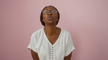 Gözlüklü bir kadın pembe bir arka planda öpüşüyor.