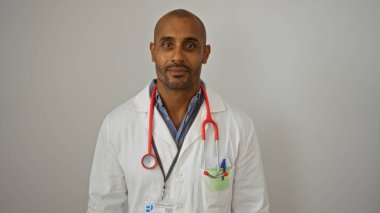 Beyaz önlüklü, beyaz arka planda steteskobu olan yakışıklı Afro-Amerikan erkek doktor.