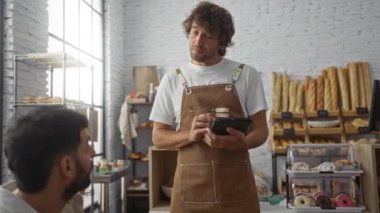 Baker, ekmek ve hamur işleriyle dolu bir pastanede tablet kullanarak müşteriyle iletişim kuruyor.