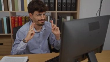 Ofisteki İspanyol adam parmaklarını çapraz yapıp bilgisayarın önünde başarıyı kutluyor..