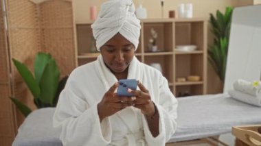 Genç bir kadın, yeşil çiçekli ve masaj masalı sessiz bir kaplıca odasında bornoz giyiyordu.