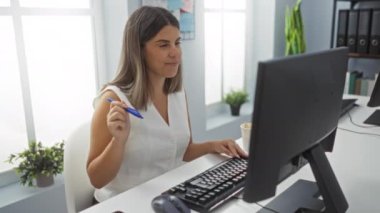 Ofis masasındaki başarısını bilgisayar ve kalemle kutlayan kadın, neşe ve memnuniyet gösteriyor.