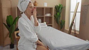 Parlak, rahat bir sağlık odasında bornoz giyerken spa salonunda dinlenen bir kadın.