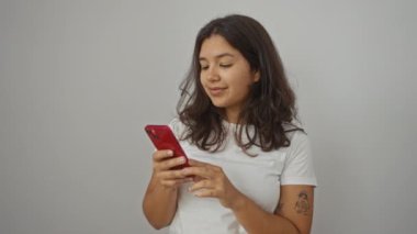 Akıllı telefon kullanırken güvenle gülümseyen genç İspanyol kadın. Mutlu ve pozitif. Beyaz arka planda izole edilmiş.
