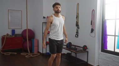 Spor aletleriyle spor salonunda esneyen genç bir adam. Güneşli bir günde spor topları, halatlar ve direniş bantları da dahil.