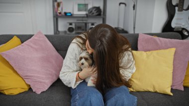 Genç bir İspanyol kadın sıcak bir kanepede bisikletli Yorkshire Teriyeri 'ne sevgiyle sarılıyor..
