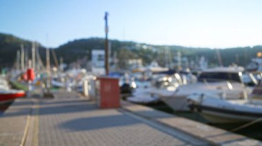 Odaklanmış tekne ve rıhtımları, berrak mavi bir gökyüzünün altında, manzaralı dağ manzaralı arka planda gösteren bulanık bir marina..