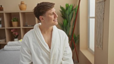 Kaplıcada dinlenmekten hoşlanan yakışıklı bir adam. Kapalı bir sağlık merkezinde beyaz bornoz giyiyor.