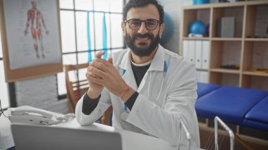 Klinikte sakallı, gülümseyen bir erkek doktor..