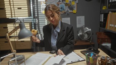 Kafkas kadın dedektif dağınık polis ofisinde donut yiyor.