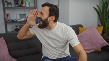 Modern bir oturma odasında bağıran sakallı neşeli, orta yaşlı bir adam.