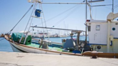Bulanık balıkçı teknesi rıhtıma yanaştı. Arka planda marina ve açık mavi gökyüzünü gösteriyor..