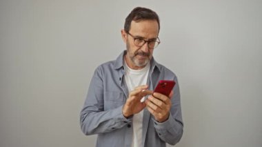 İspanyol asıllı, orta yaşlı, parmakları aşağıda olan akıllı telefon kullanıyor olumsuz bir hoşnutsuzluk ve reddedilme işareti var, izole beyaz arka planda kızgın bir ifade.