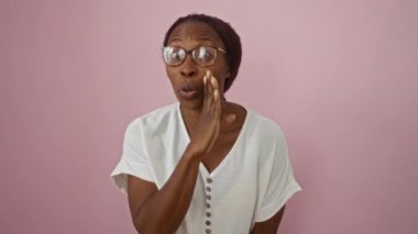Gizli fısıltılar, gözlüklü genç Afro-Amerikalı kadın pembe arka planda dikiliyor, dedikodu yapıyor ve sohbet ediyor, ağızdan ağıza özel konuşmaları paylaşıyor.