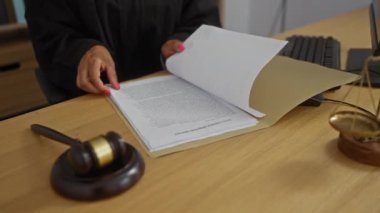 Masasında tokmakla çalışan bir kadın yasal belgeleri inceliyor..