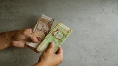 Peru tabanlarını beton bir duvara dayayan eller, 100 ve 20 sol da dahil olmak üzere birden fazla banknot gösteriyor.