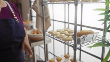 Fırında telefonla konuşan bir kadın. Ekmek ve pastanelerde pastaneler. Parlak bir iç mekanda, pencerelerden içeri ışık sızıyor.