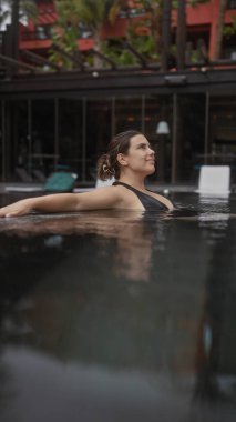 Huzurlu bir bali tatil köyünde dinlenen sakin bir kadın tropikal bir ortam ve Asya mimarisi ile