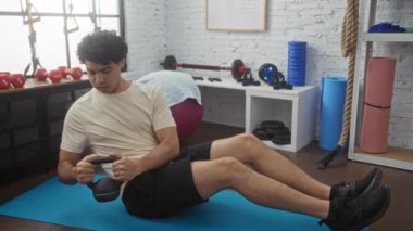 Genç İspanyol adam spor salonunda egzersiz yapıyor, halterle mekik çekiyor. Spor salonundaki spor salonuna odaklanıyor.