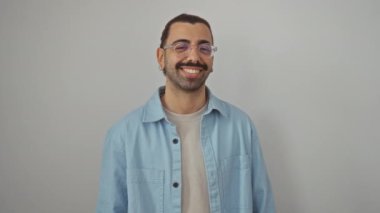 Kot gömlek giyen genç İspanyol adam pozitif onay işareti ile gülümsüyor, izole edilmiş beyaz arka plan üzerinden mükemmel titreşimler yayıyor.