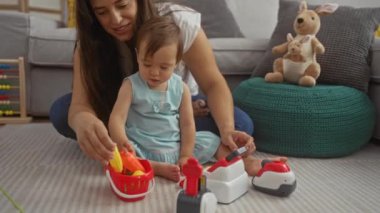 Anne kızıyla oturma odasında oyuncaklarla oynuyor, aile anlarını sergiliyor ve rahat bir evde aşk yaşıyor.