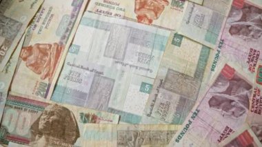 Mısır banknotları dağınık, beş, on ve iki yüz sterlin de dahil olmak üzere çeşitli mezhepler sergiliyor, Mısırın kültürel ve ekonomik unsurlarını vurguluyor.
