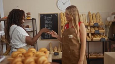 Kadın fırınlarda gülümseyen fırıncılar arkalarında ekmek ve hamur işleri sergilenerek arkadaşça sohbetler ve takım çalışması yapıyorlar.