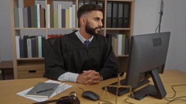 Yargıç cüppeli genç İspanyol adam ofisteki bilgisayara odaklanmış.