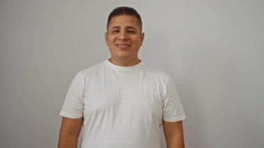 Beyaz gömlekli genç bir adam öpüşüyor, izole edilmiş beyaz bir arka plana güvenle gülümsüyor.