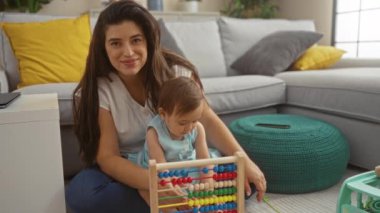 Anne, küçük kızıyla oturma odasında renkli abaküs kullanarak oynuyor. Etrafı rahat iç ve aydınlık yastıklarla çevrili. Aile bağlarını ve evdeki sevgiyi gösteriyor.