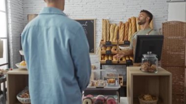 Baker, arka planda taze ekmek rafları olan fırında müşteriye yardım ediyor.