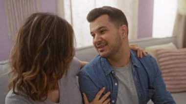 Kadın ve erkek, evdeki kanepede öpüşürler. Sıcak bir oturma odasında sevgilerini ve ilişkilerini gösterirler..