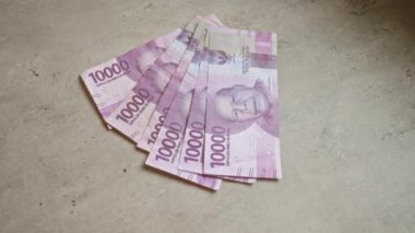 Endonezya rupia banknotları, temiz bir düzende detaylı bir portreyle birlikte 10000 parçalık beton bir yüzey sergiliyor.