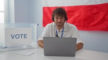 Genç İspanyol adam, Polonyalı üniversitesinde kulaklıklı bilgisayar kullanırken ağzı ve gözleriyle çılgın balık suratı yapıyor.