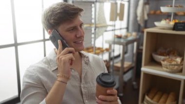 Genç adam, elinde kahve fincanıyla fırının içinde konuşuyor. Arkasında da bir sürü hamur işi var.