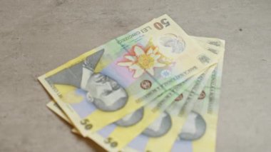 Romen 50 lei banknotları, her bir banknottaki canlı tasarım ve portreyi vurgulayarak somut bir zemine saçıldı.