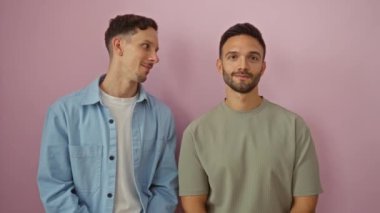 Eşcinsel çift pembe bir arka planda fısıldıyor ve gülüyor. Aşklarını ve mutluluklarını birlikte sergiliyorlar.