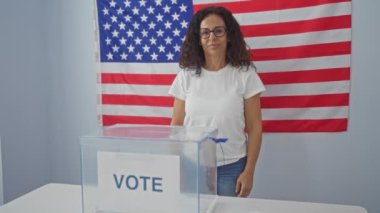 Amerikan seçim koleji, orta yaşlı İspanyol kadın oy pusulasının yanında duruyor, gülümsüyor ve işaret ediyor tamam işaret parmağıyla, arkadaşça ve mükemmel katılımı simgeliyor