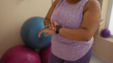 Spor salonunda spor salonunda spor salonunda spor topları ve bitkilerle çevrili mor askılı tişört giyen yetişkin ve iç mekan odaklı bir kadın..