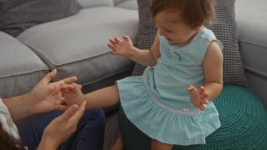 Oturma odasındaki kanepede küçük kızla oynayan bir kadın aile sevgisini ve birlikteliğini gösteriyor.
