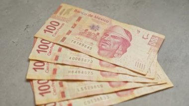 Üzerinde 100 peso banknot bulunan desenli beton bir yüzeye yerleştirilmiş Meksika banknotları. 