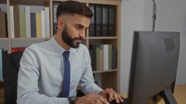 Ofis odasında çalışan genç bir adam, arka planda rafları olan, kravat takan ve ekranda profesyonel ve çalışkan bir tavır sergileyen genç bir adam.